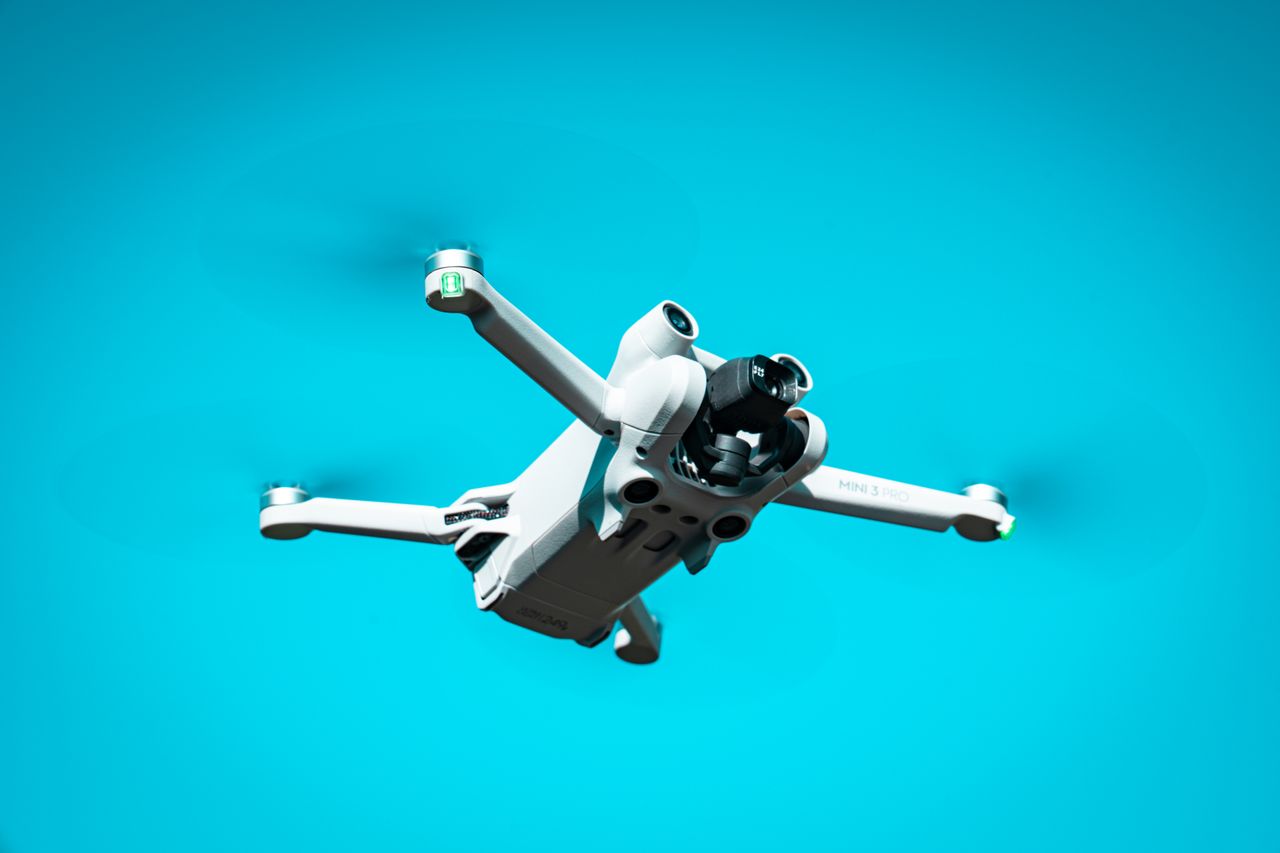 hero-gallery-01 A modern drone flying against a vibrant blue sky, showcasing advanced technology in motion.